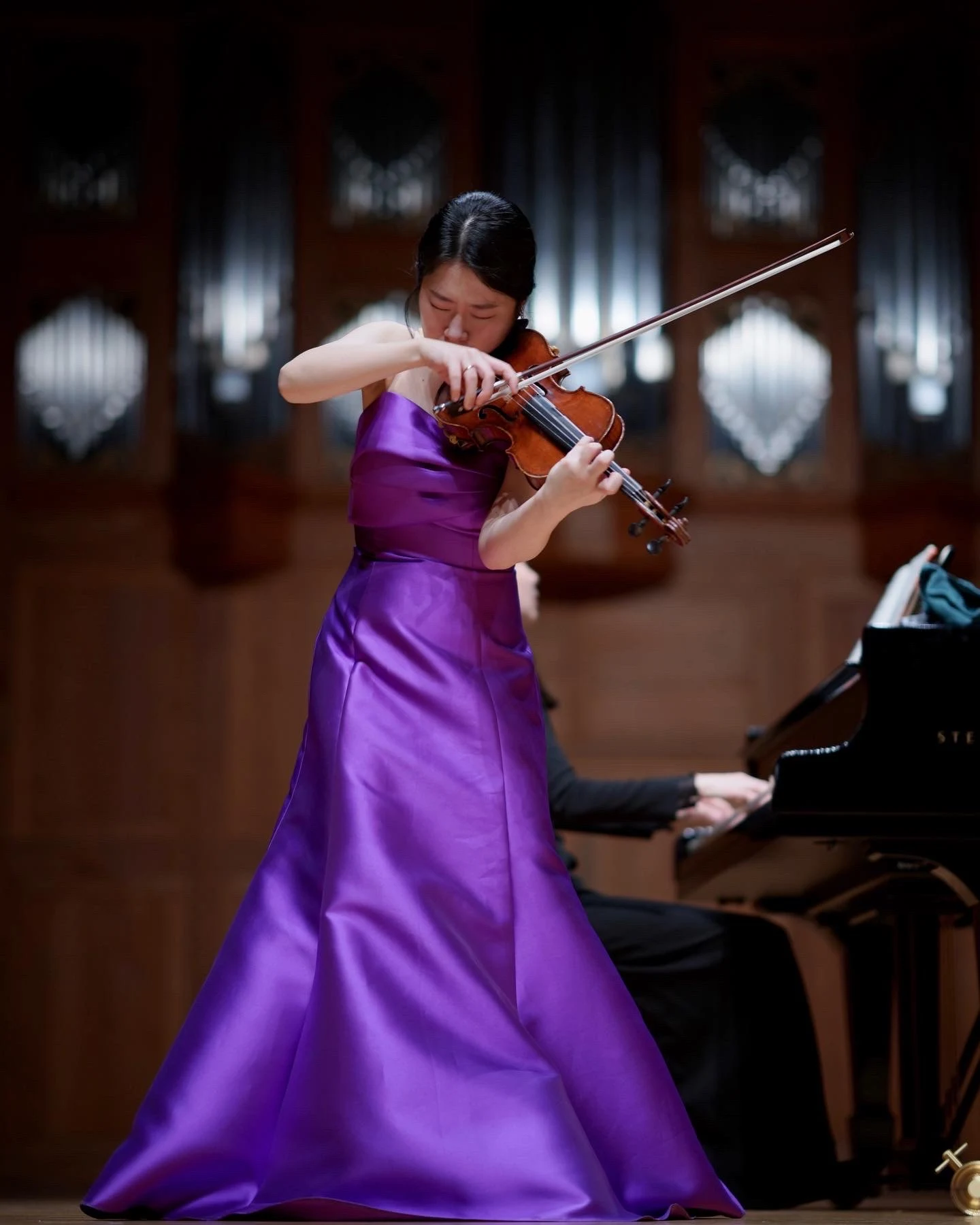 Byeol Kim performing violin on stage in a purple gown