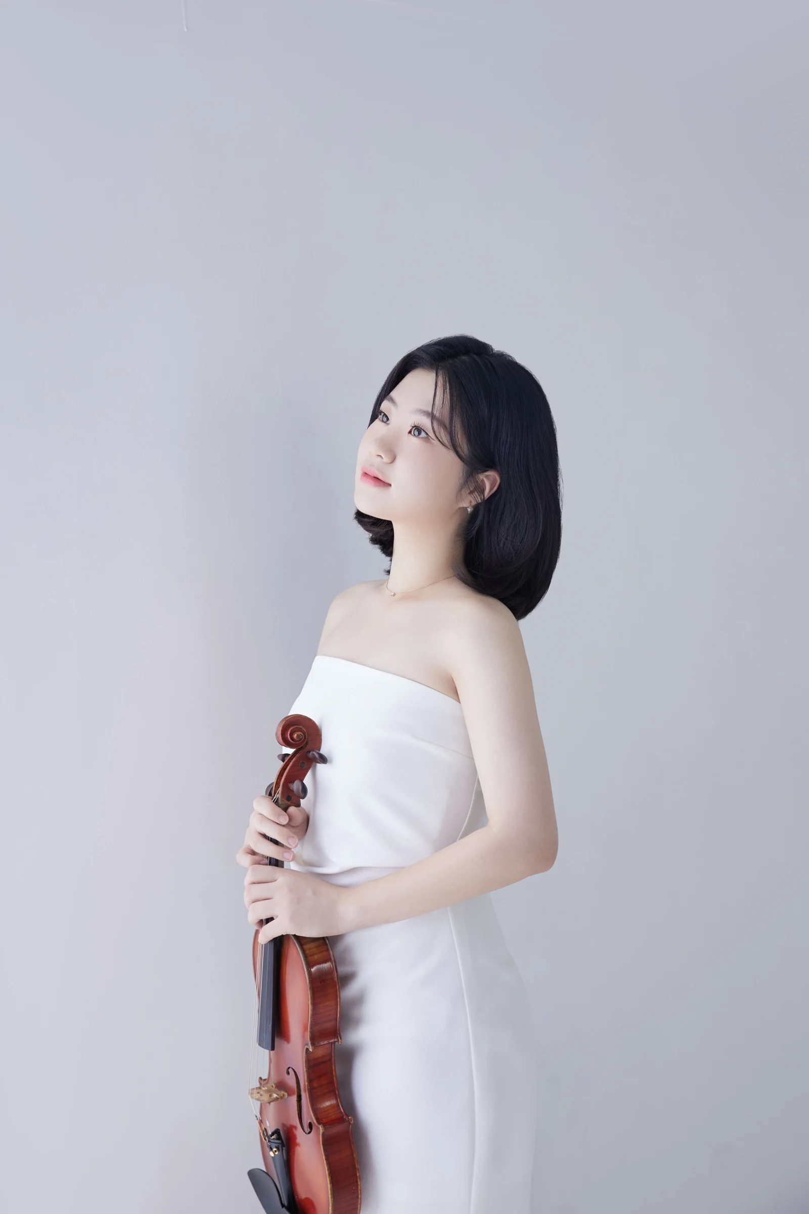 Full-length portrait of Byeol Kim in a white dress holding her violin